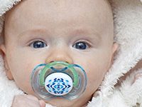 Fotografía de bebé con una chupeta en su boca.